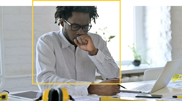 Man sitting at a desk coughing